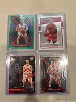 Photo of four Malachi Flynn rookie cards in clear plastic protective cases with team colors red and white, showing varied designs including holographic and prism reflective styles