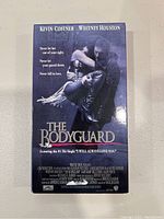 Front cover of The Bodyguard VHS tape showing Kevin Costner holding Whitney Houston, title and marketing text.