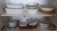 Wide shot showing most of the baking dishes, bowls, and serving tray packed inside a cabinet shelf.