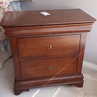 Front view showing two drawers with brass hardware and molded edges on the nightstand.