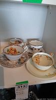 Photo of four teacups and saucers with floral designs in vintage style with gold accents, showing condition and details.