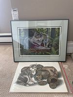 Framed print featuring a wolf and a pup in woodland setting with an unframed print of a husky and rustic wood baskets beneath it.