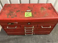 Red aluminum toolbox with multiple drawers and worn surfaces