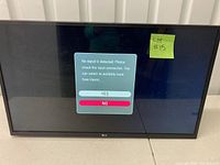Front view of LG 32 inch flatscreen TV powered on showing an on-screen menu with no signal detected message. Black bezel. Screen is glossy.