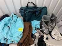 Photo showing light blue Spyder youth ski jacket, brown ski pants, blue-green L.L. Bean ski boot carry bag, grey Technica ski boots, and various gloves and hats.
