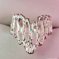 Close-up front view of the silver open wave loop ring showing texture and shape