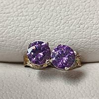 Front view of 14K white gold earrings showing round purple amethyst gemstones set with prongs.