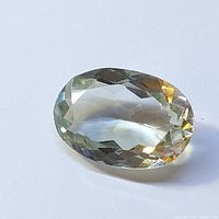 Oval cut green amethyst gemstone shown on white background highlighting clarity and facets