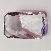 Top view of large clear light purple amethyst gemstone with faceted surface in rectangular shape.