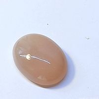 Oval brown moonstone cabochon gemstone with polished surface, showing warm brown color with internal reflective qualities.