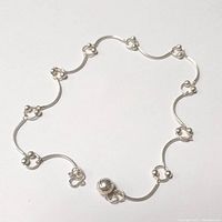Photo of sterling silver anklet arranged flat showing decorative circular links and clasp.