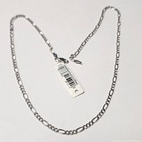 Full view of the silver chain bracelet laid in a circular shape, showing the entire 20-inch length and attached price tag.