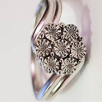 Close-up photo showing seven round stones with a starburst cut pattern on a silver ring band with a split design.