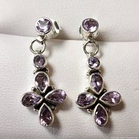 Front view of silver amethyst earrings showing round and pear-shaped amethyst stones set in polished silver metal.