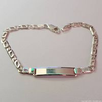 Full view of silver bracelet showing ID plate and chain links with lobster clasp.