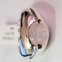 Close-up front angled view of the silver ring with the rose quartz gemstone, showcasing the polished band and faceted light pink stone.