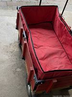 View of the inside of the wagon showing red fabric liner and wooden sides in used condition