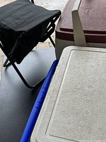 Photo showing top view of black folding chair and two cooler lids, one white lid and one maroon lid cooler