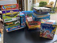 Stack of board games including Trouble, Monopoly, and Pop-Up Pirate.