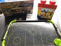 Tabletop air hockey game, LEGO set and remote control car box shown together