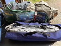 Large assorted camping gear packed in several bags and carrying cases, including tents and other camping equipment.
