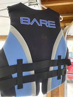 Front side of a blue and black BARE lifejacket showing straps and design.