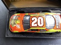 Top view of the Tony Stewart 1/24 scale diecast NASCAR car showing racing number 20 and sponsor logos Home Depot and SUPREME on the orange-yellow car body. Car is inside foam padding of black display box.