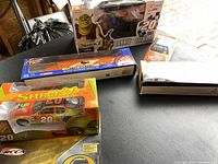 Overview of the lot showing the boxed diecast cars, Shrek 2 Donkey/Stewart figurine box, and additional NASCAR memorabilia.