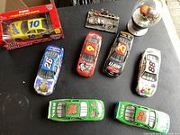 Overview of eight Nascar diecast cars, seven loose and one boxed, with a clear glass dome collectible trophy car.