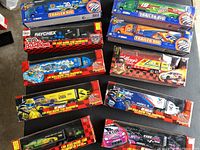Photo showing all 10 NASCAR 1/64 scale toy hauler boxes stacked, displaying variety of team transporter models with team colors and logos.