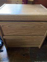 Front view of oak side table showing drawer fronts and wood grain.