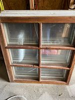 Front view of one old wooden window showing 6 intact glass panes and wood frame.