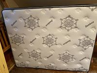 Top view of mattress showing white surface with dark gray floral motifs and 'Bamboo' text