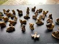 Photo showing 33 assorted ceramic miniature animal figurines from Tetley Tea collection on a black surface under natural light.