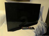 Photo of the 24-inch black Scepter TV with a matching remote placed in front of it.