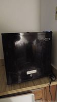 Black upright Whynter freezer closed, showing exterior with brand label and lock at bottom.