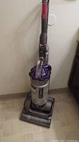 Full front view of Dyson DC25 upright vacuum cleaner, showing handle, dust container, and floor head.