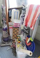 Photo showing Dyson Animal Ball vacuum, storage containers, welcome mat, American flag, and scattered household items.