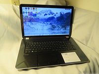 HP Pavilion laptop powered on showing Windows 8 desktop screen with starter icons and background image of mountains and glacier.