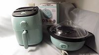 Dash Air Fryer with front dial and handle, Nostalgia Popcorn Maker with dome lid, Nostalgia Waffle Maker, all on a flat surface
