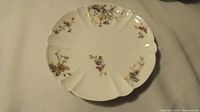 Top view of a porcelain plate with scalloped edges and floral patterns.