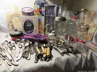 Overview of the kitchen items shown on a table including cutlery, utensils, jars, cutting boards, and cookware.
