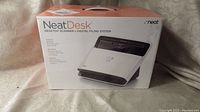 Box of the NeatDesk Desktop Scanner showing product image and branding along with product features like scanning receipts, business cards, and tax documents.