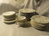 Photo showing the full set of stacked 12 saucers, 10 plates, and 2 cups with pink floral decoration in various patterns