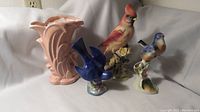 Four different bird figurines and a pink swan-shaped McCoy vase displayed together