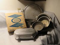 Photo showing the vintage aluminum cookware including pots, pan, and the closed waffle baker with original box behind.