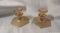 Two hexagonal base pink rose cranberry glass candlestick holders with etched decorative patterns.