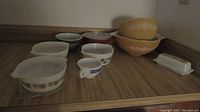 Photo showing entire set of Pyrex items including cups, casseroles with lids, butter dish, and bowls arranged on a shelf