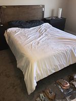 Wide view of assembled queen bed frame with fitted sheet and bedding