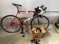 Overall view of red and white LeMond Proprad cyclocross bike with pump, box of accessories, and cycling shoes